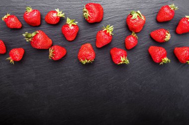 Olgun çilek siyah bir zemin üzerine üst üste düzenli bir şekilde düzenlenmiş. tex için alan