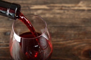 Bir bardağa kırmızı şarap dök, ahşap bir arka plana, Tex için yer aç.