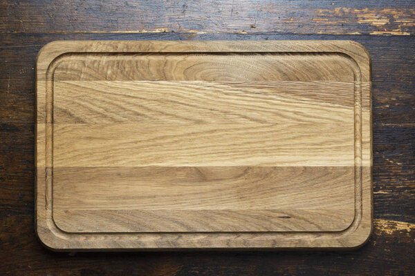 Rectangular wooden cutting board on a wooden table. space for tex