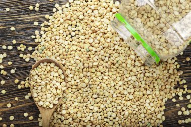 bir kaşık çiğ kuru bezelye ve kahverengi ahşap bir masa üzerinde dağınık. tex için alan