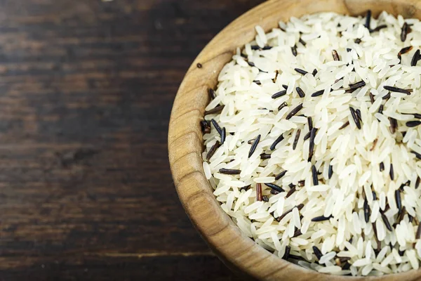 Black and white wild rice in a wooden plate on a wooden background. space for tex