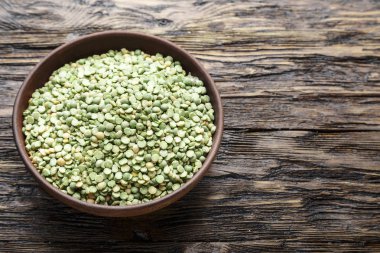 Kahverengi ahşap bir masa bir tabağa ham kuru bezelye. tex için alan