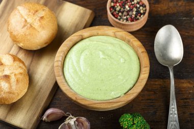 ahşap bir masa üzerinde öğle yemeği brokoli çorbası. Yakınlarda ekmeği ve baharat bulunmaktadır