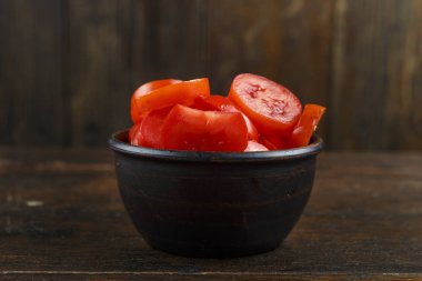 Kırmızı kiraz domates kahverengi ahşap bir masa bir tabağa dilimlenmiş. tex için alan