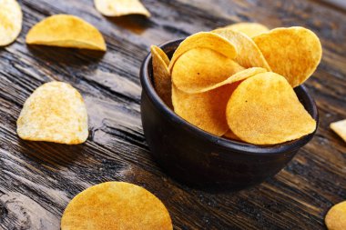 ahşap bir tabloda bir kil tabak patates cipsi. tex için yer