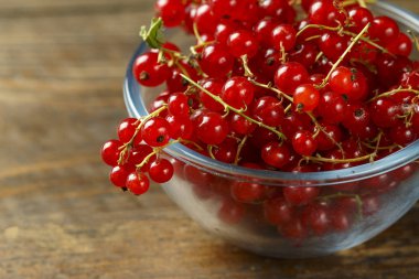 kahverengi ahşap bir masa bir plaka üzerinde kırmızı kuş üzümü. rustik arka plan. tex için alan