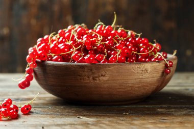 kahverengi ahşap bir masa bir plaka üzerinde kırmızı kuş üzümü. rustik arka plan. tex için alan