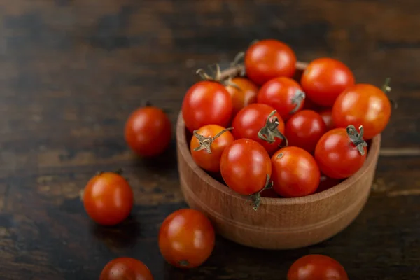 Red cherry tomatoes in a plate on a brown wooden table. space for tex