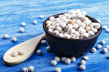 Kase ve ahşap masa üzerinde kuru nohut kaşıkla.