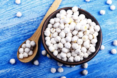 Kase ve ahşap masa üzerinde kuru nohut kaşıkla.