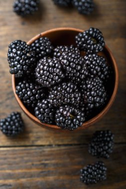 bir ahşap arka plan ve scattere kil tabağa böğürtlen