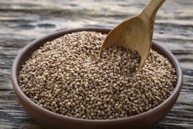 ahşap arka plan üzerinde bir kil plaka ham karabuğday kabuğu çıkarılmış tane. Woo