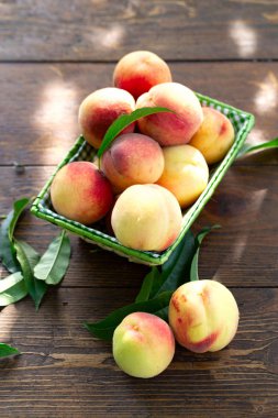 Koyu ahşap rustik sepet içinde yaprakları ile taze şeftali meyve