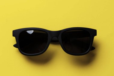 Sarı arka planda siyah güneş gözlüğü.