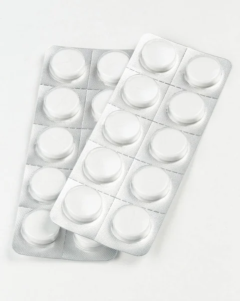 White pills in a blister on white background — Stock Photo, Image