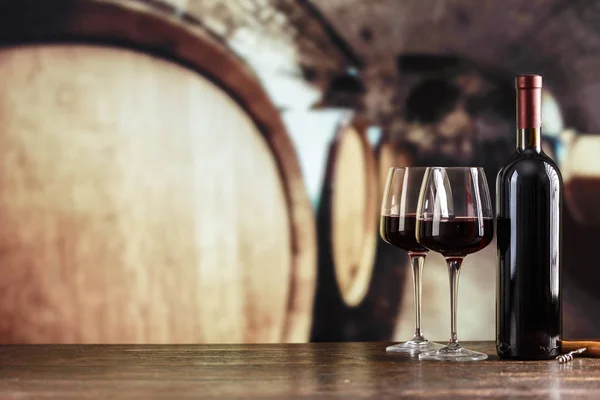 En copas de vino tinto sobre un fondo de barricas grandes — Foto de Stock