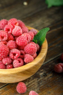 Ahşap bir masa üzerinde ahşap bir kapta taze ahududu