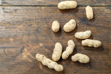 Kahverengi ahşap zemine serpiştirilmiş kabuklu fıstıklar. Geleneksel bira atıştırması. tex için yer