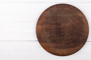 Beyaz ahşap arka planda kahverengi yuvarlak kesim tahtası. Yukarıdan bak. Metin için yer.