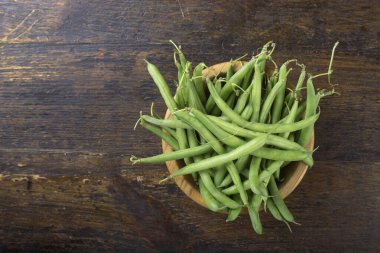 Kahverengi ahşap arka planda, tabakta taze kuşkonmaz fasulyesi.