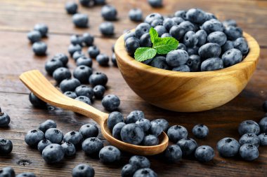 Tahta bir masada, ahşap kasede taze toplanmış yabanmersini. Sağlıklı meyveler. Yabanmersini antioksidan..