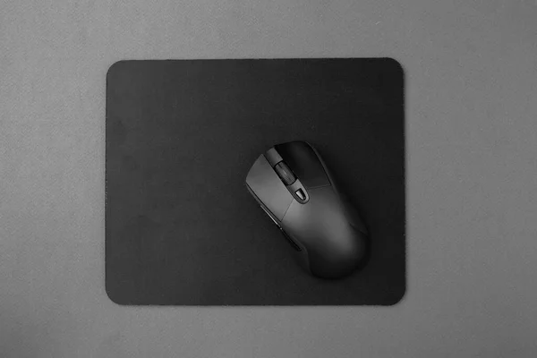 Black wireless mouse on a mouse pad, top view.