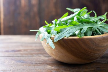 Tahta tabakta taze yeşil roka salatası var. Basit bir kırsal grup