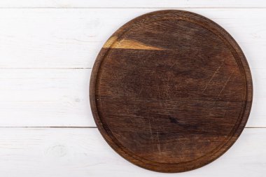 Beyaz ahşap arka planda kahverengi yuvarlak kesim tahtası. Yukarıdan bak. Metin için yer.
