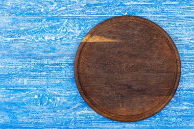 Mavi arka planda yuvarlak kesim tahtası. Yukarıdan görüntüle.