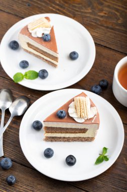 Masada kremalı kek var. Yaban mersinli pastanın yanında.