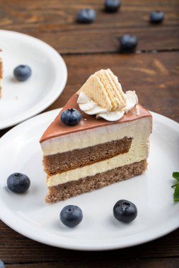 Masada kremalı kek var. Yaban mersinli pastanın yanında.