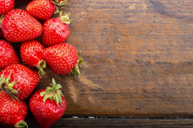 Olgun organik çilekler kahverengi ahşap bir arka planda sıralanmış. tex için yer