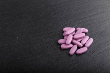Siyah arka plan üzerine serpiştirilmiş pembe oval haplar. Hastalığın tıbbi tedavisi