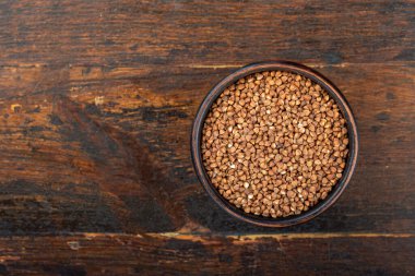 Ahşap bir arka planda kil bir kasede karabuğday.