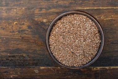 Ahşap arka planda kil bir kasede keten tohumu. Hasat..