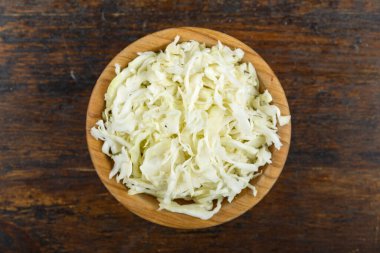 Ahşap arka planda bir kasede doğranmış lahana. Sebze, malzeme ve zımba. Sağlıklı yemek..