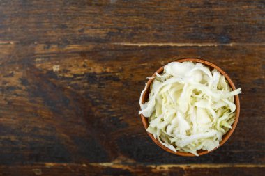 Ahşap arka planda bir kasede doğranmış lahana. Sebze, malzeme ve zımba. Sağlıklı yemek..