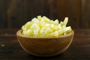 Ahşap arka planda bir kasede dilimlenmiş çiğ sarı biber. Sebze, malzeme ve zımba. Sağlıklı yemek..