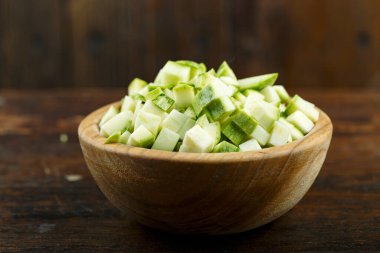 Ahşap arka planda bir kasede dilimlenmiş kabak. Sebze, malzeme ve zımba. Sağlıklı yemek..