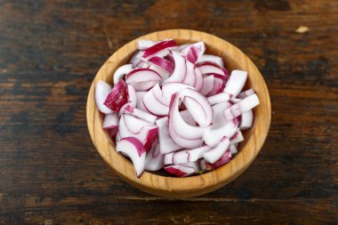 Ahşap arka planda bir kasede dilimlenmiş kırmızı soğan. Sebze, malzeme ve zımba. Sağlıklı yemek..