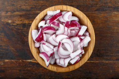 Ahşap arka planda bir kasede dilimlenmiş kırmızı soğan. Sebze, malzeme ve zımba. Sağlıklı yemek..