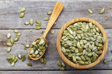 Kabak çekirdekli kase ve ahşap bir masada tahta kaşık..