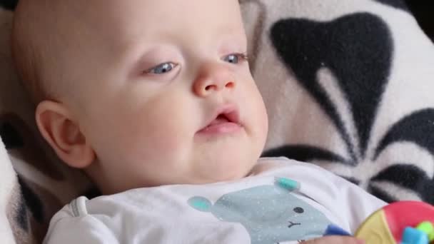 Baby met een plastic knaagdier zit in een kinderstoel. — Stockvideo