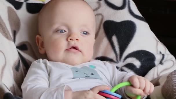 Baby met een plastic knaagdier zit in een kinderstoel. — Stockvideo