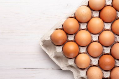 Ahşap bir arka planda karton tepside kırmızı tavuk yumurtası. tex için yer