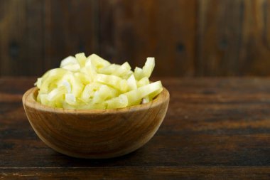 Ahşap arka planda bir kasede dilimlenmiş çiğ sarı biber. Sebze, malzeme ve zımba. Sağlıklı yemek..