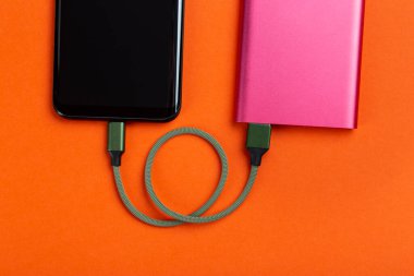 Elektrik bankasıyla çalışan akıllı telefon. Mobil cihazları şarj etmek için taşınabilir güç bankası. Batarya bankası.