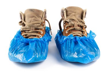 Beyaz arka planda izole edilmiş erkek ayakkabıları üzerindeki mavi koruyucu ayakkabı kılıfları. Tıp kurumlarında hijyen ve temizlik.