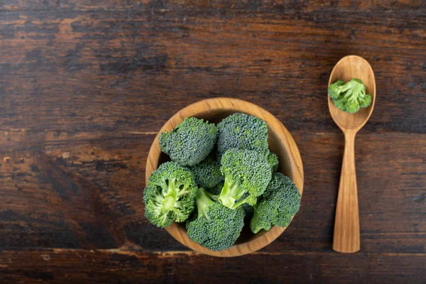 Fresh broccoli with in bowl on wooden table close up. Fiber-rich food.