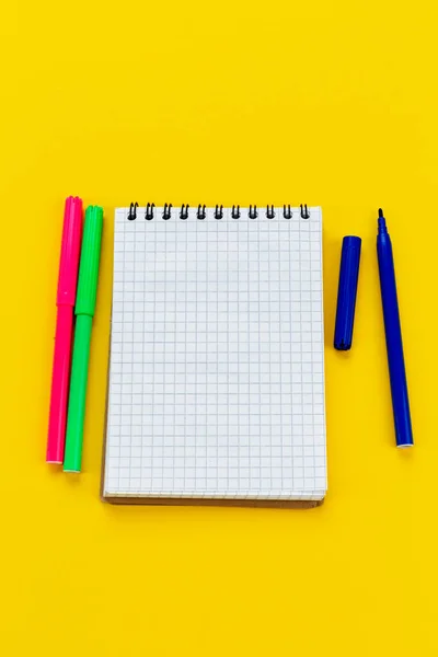 School supplies. Notepad and markers on a white background. View from above.